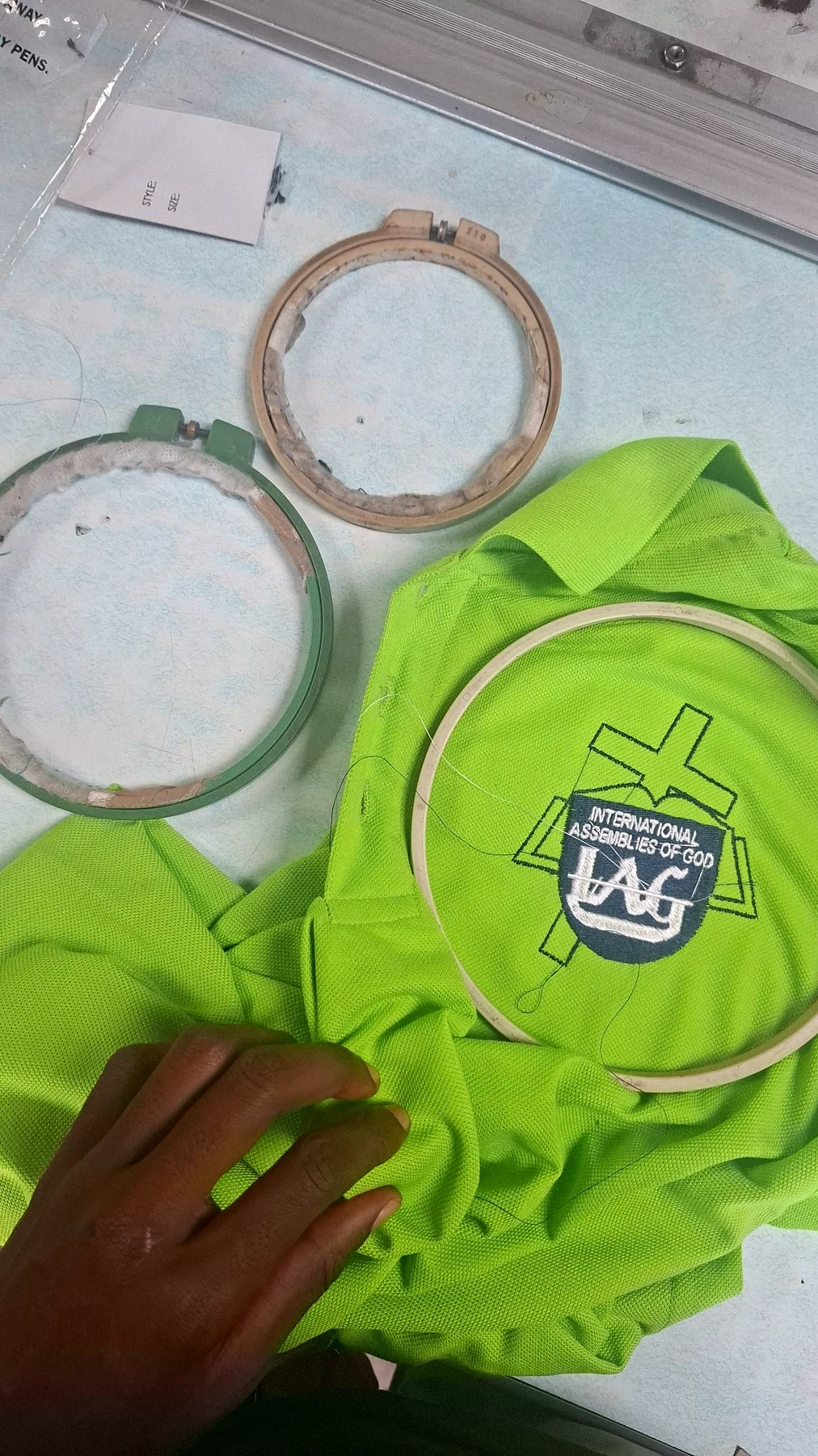 Logo embroidery in progress on a green uniform.