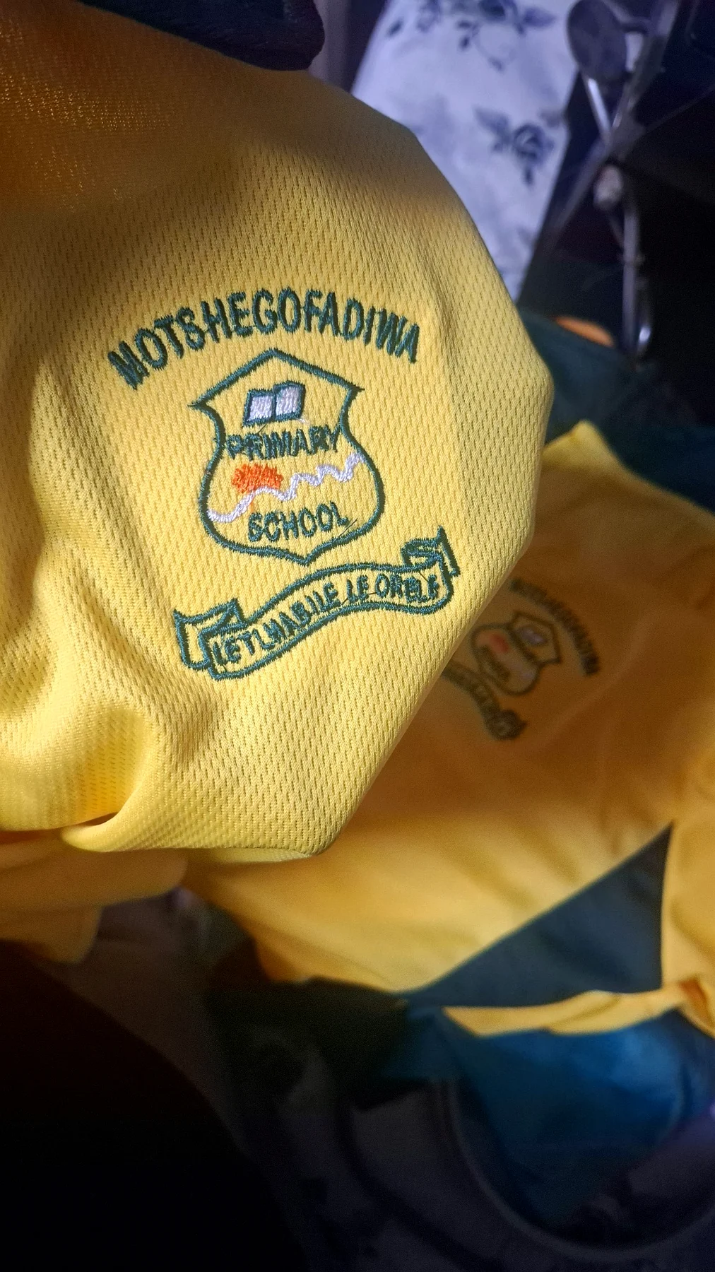 Finished embroidered school crest on yellow uniform fabric.