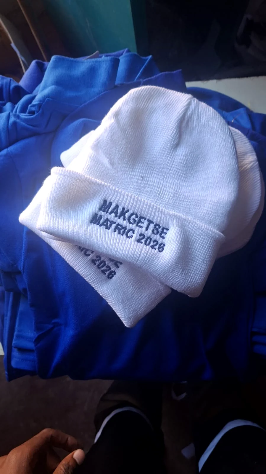 White knit beanies embroidered with a commemorative message.