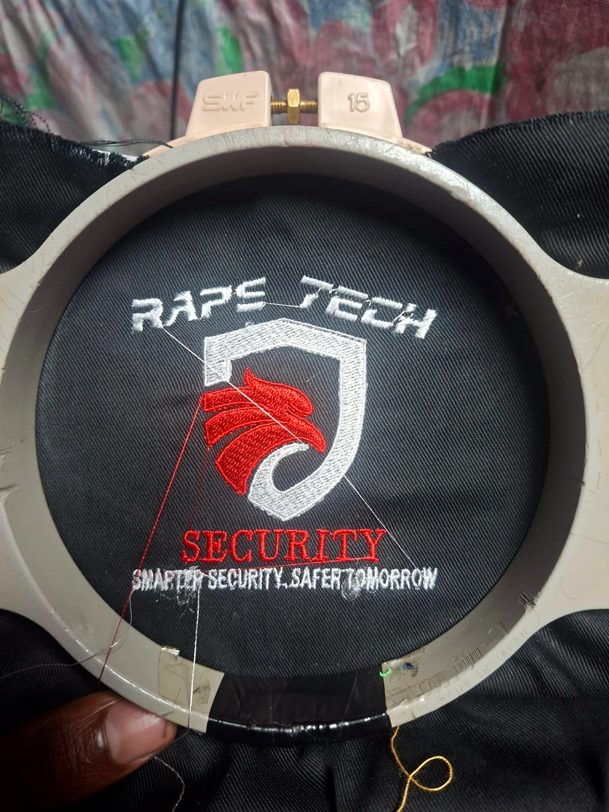 Security-company logo being embroidered in the hoop.