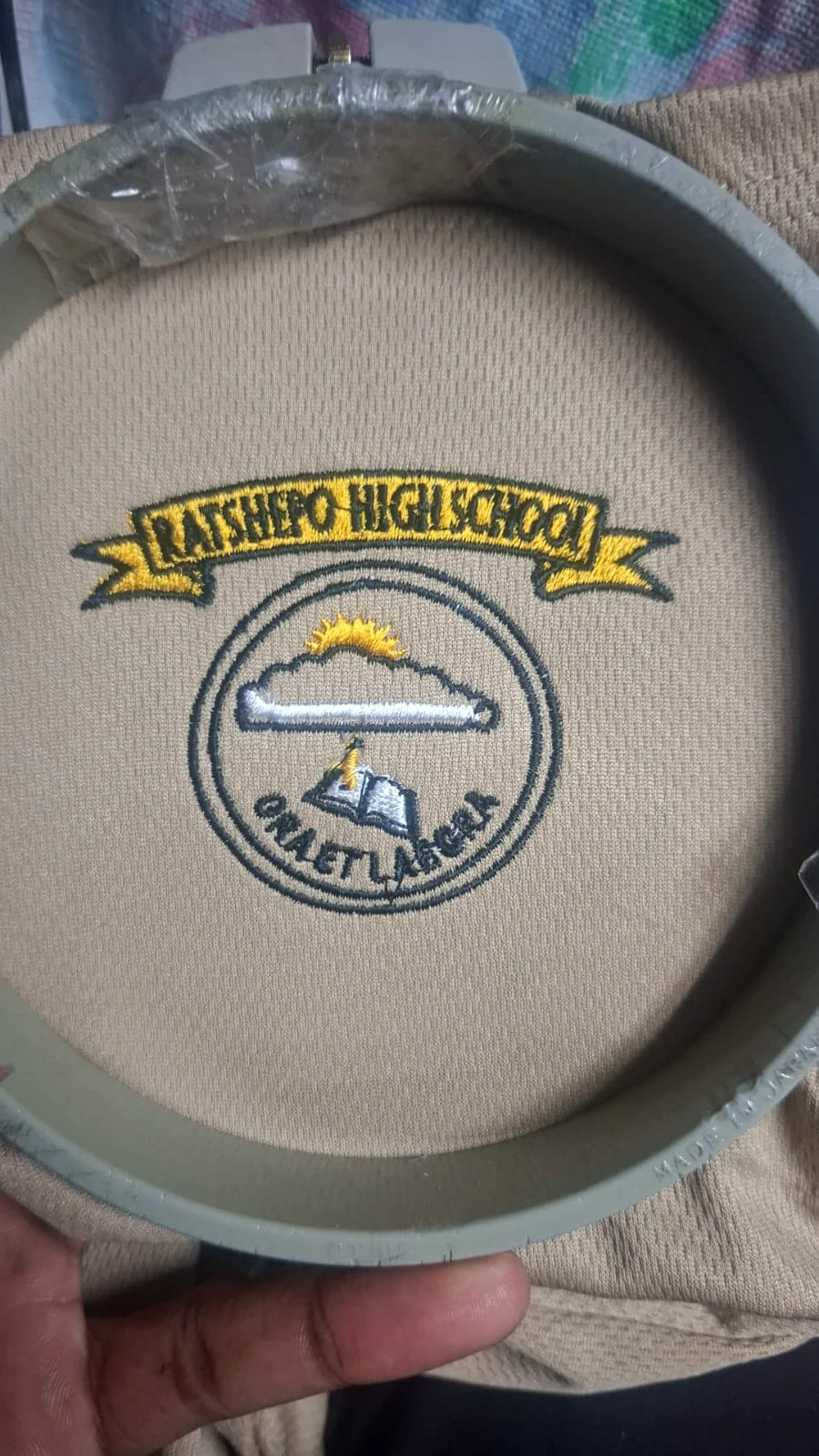 School emblem being stitched onto uniform fabric.