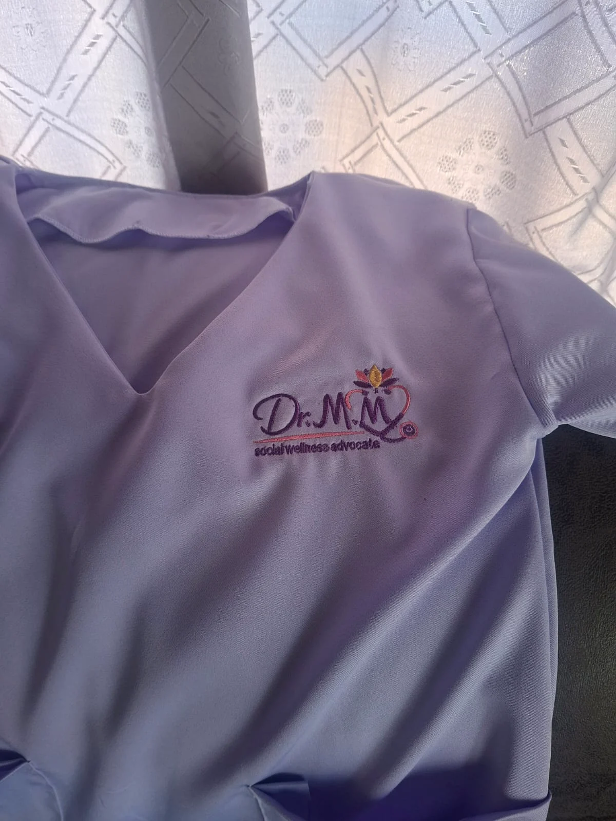 Custom embroidered wellness logo on a scrub top.