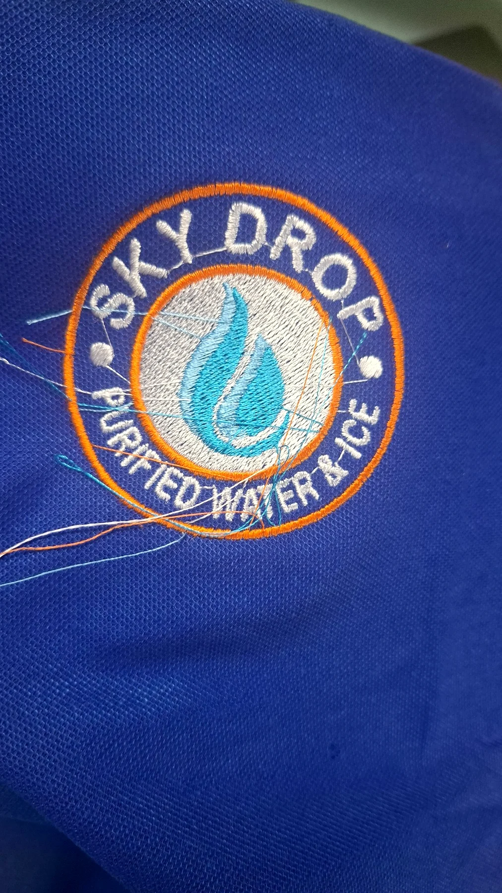 Embroidered school emblem on blue uniform fabric.